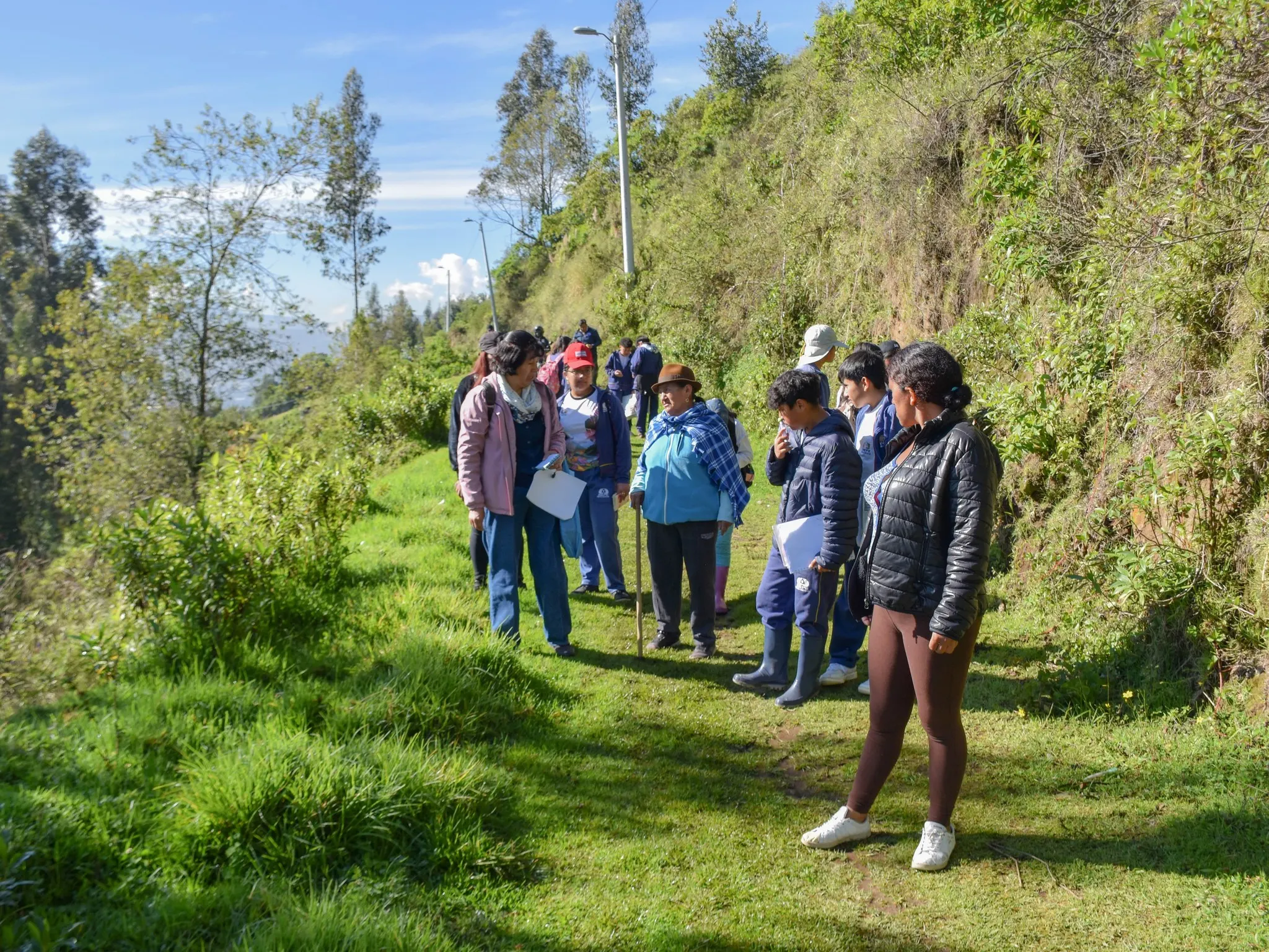 Mujer de la comunidad compartiendo saberes ancestrales con docentes y alumnos del INEPE durante una caminata educativa en la naturaleza.